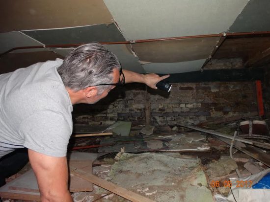 Inspecteur schijnt met een lamp langs de balken en het metselwerk in de kelder