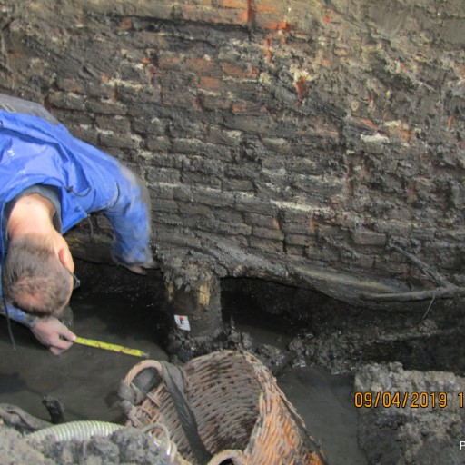 Measuring the foundation brickwork Inspector measuring the brickwork of the foundation in an excavation