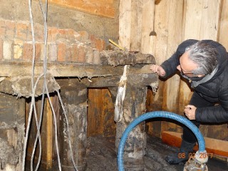 Exposed timber foundation Inspector examining an exposed timber foundation next to a pump hose