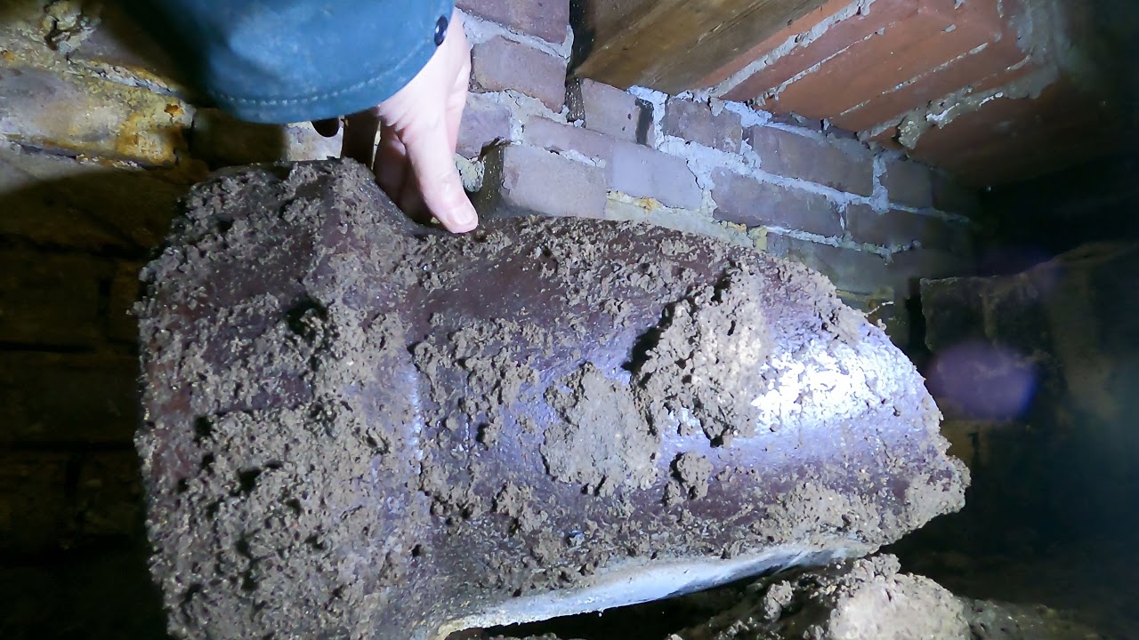Hand on an old cast-iron sewer pipe in a crawl space