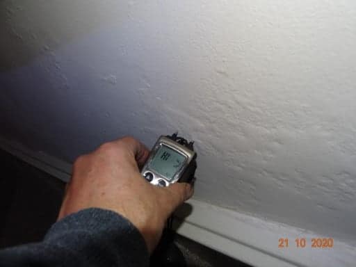 Moisture meter held against a painted wall